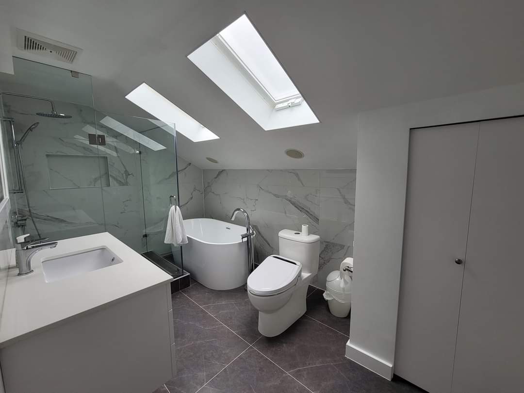 Bathroom with a freestanding tub under a skylight and large format tile