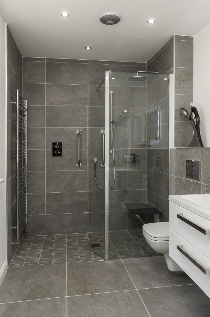 Walk in shower with framed glass beside a floating vanity