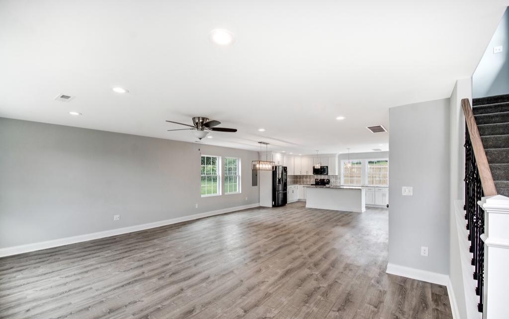 Open living area with wide plank flooring and a staircase